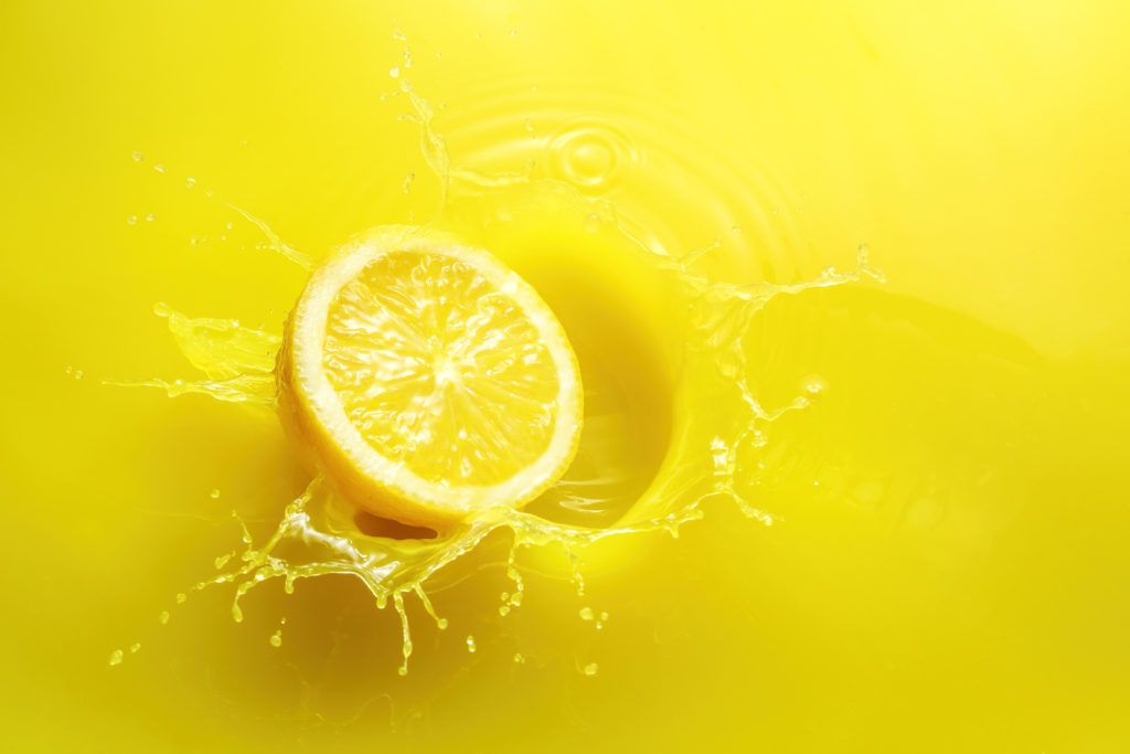 A bright yellow lemon on a yellow background.