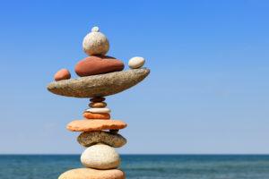 A rock cairn in front of the ocean and a blue sky.