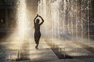 A woman dances among rows of vertical water fountains.