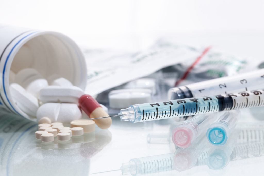 Some pills, ampules, and a syringe, showing drugs administered through different administration routes.