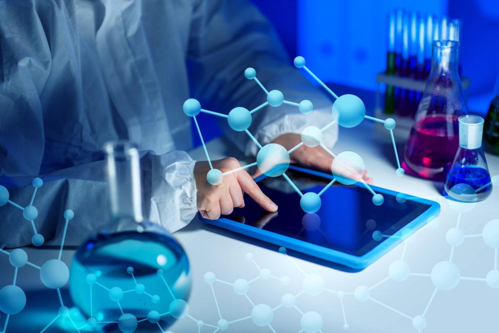 Close up of young white female scientist's hands with a tablet computer on a laboratory desktop, with abstract 3D chemical structures in the background.